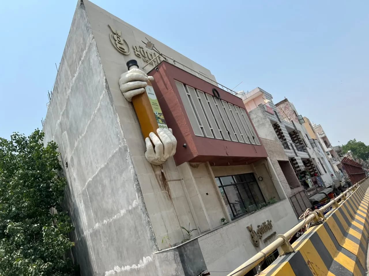 The giant sculpted hands holding a Göttlich yellow mustard oil bottle on the side of our building